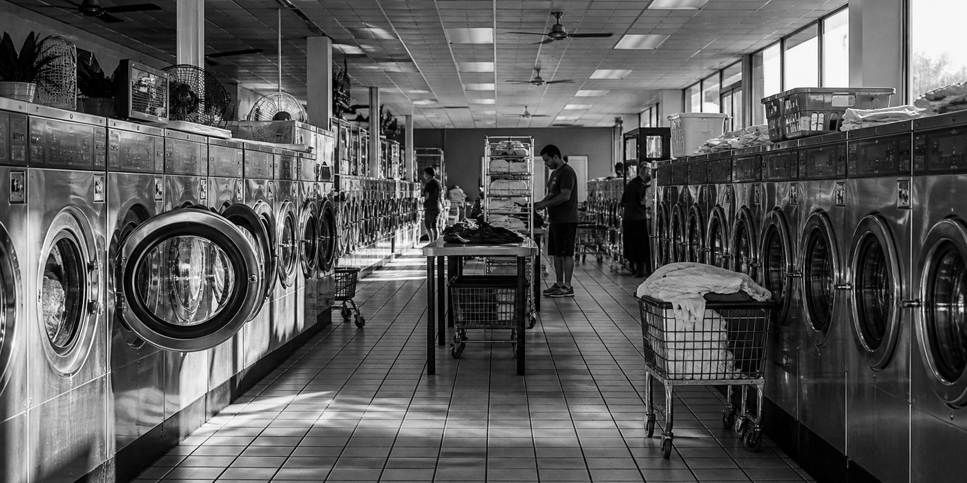 Working laundromat with rows of commercial machines and laundry carts