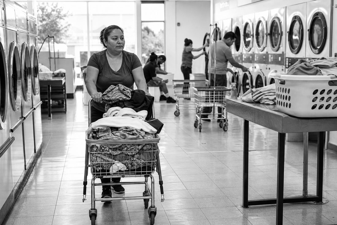 Representative established laundromat with an attendant moving a loaded cart