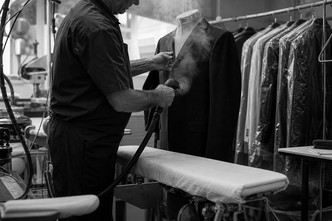 Dry-cleaning technician steaming a wool suit jacket
