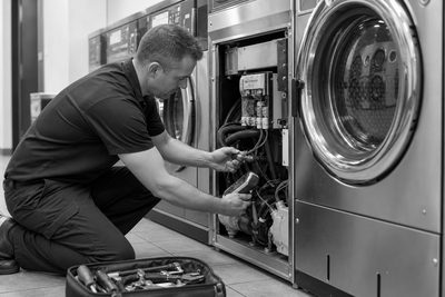 Laundry equipment technician inspecting a commercial washer